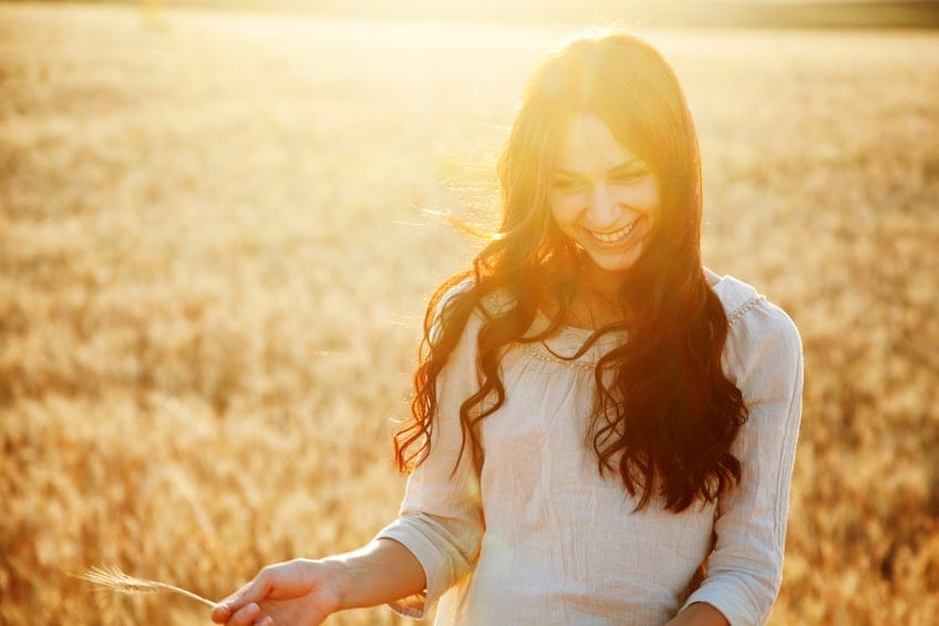 Beautiful brunette lady in wheat field at sunset