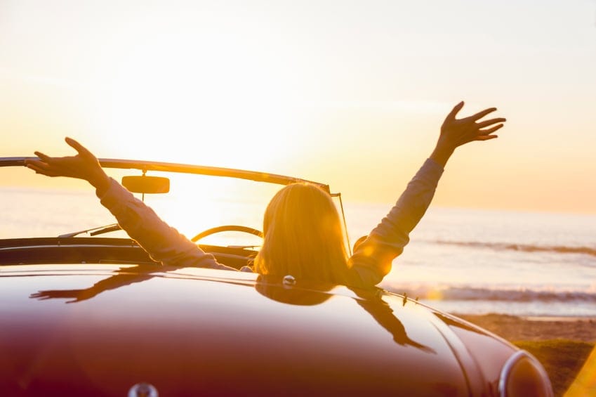Woman watching the sunset in a convertible car