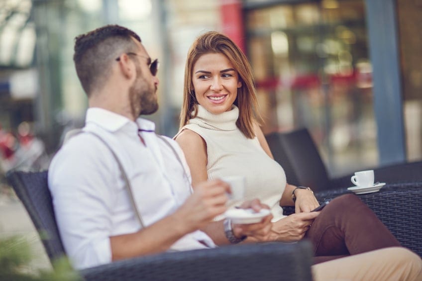 Happy businesswoman talking to her male colleague in a cafe.