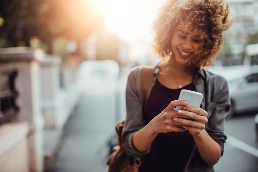 african woman texting in the street