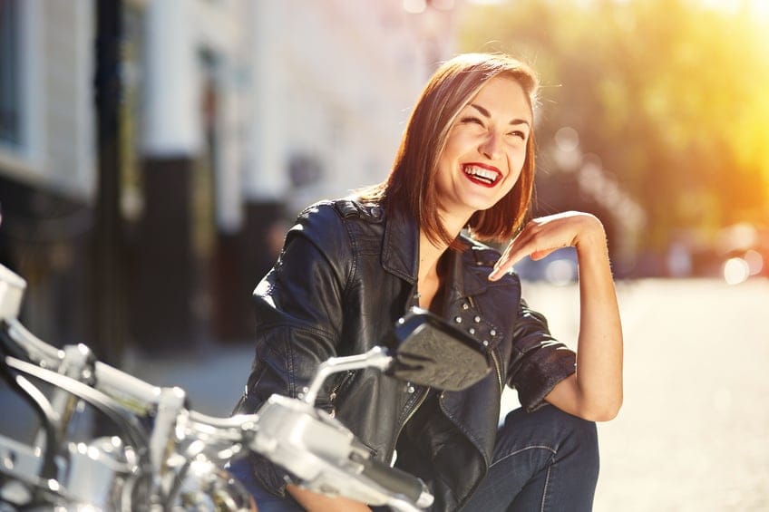 Biker girl in a leather jacket sitting on motorcycle with light leaks effect