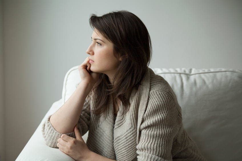 Sad girl sitting on the sofa and thinking