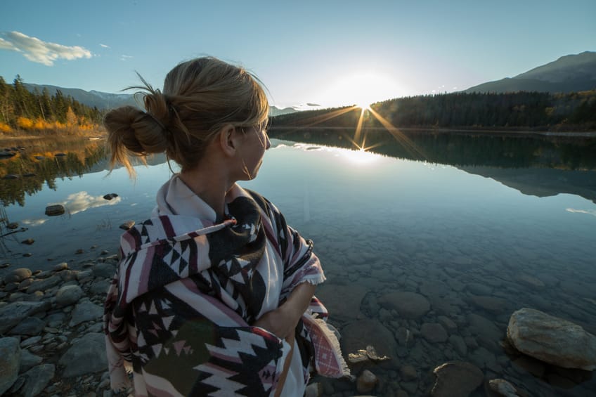 Young woman by the lake watching the sunset.