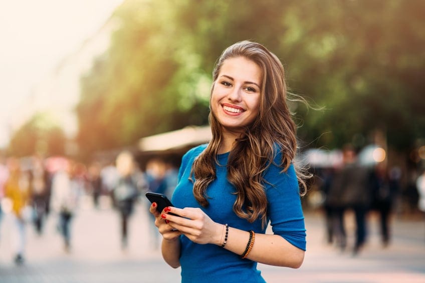 A young woman holding a mobile smiling