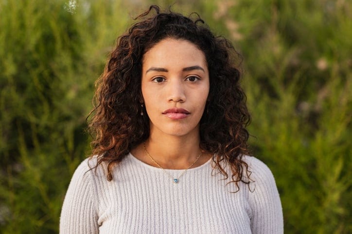 serious millennial woman outdoors green background