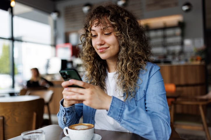 smiling woman texting in coffee shop