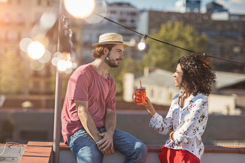 Couple talking at sunset on a rooftop party in Barcelona.