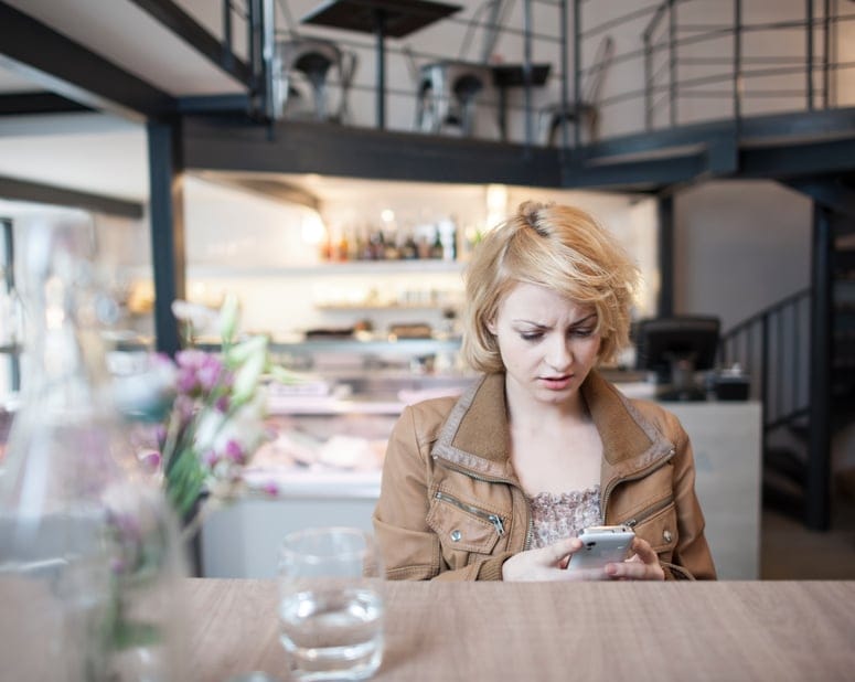woman texting annoyed at cafe
