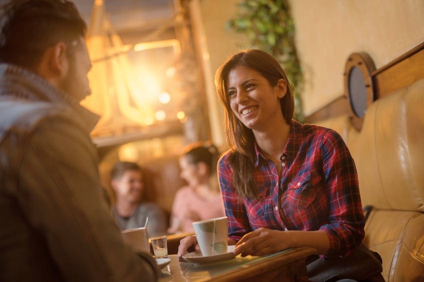 Happy woman talking to her boyfriend in a cafe.
