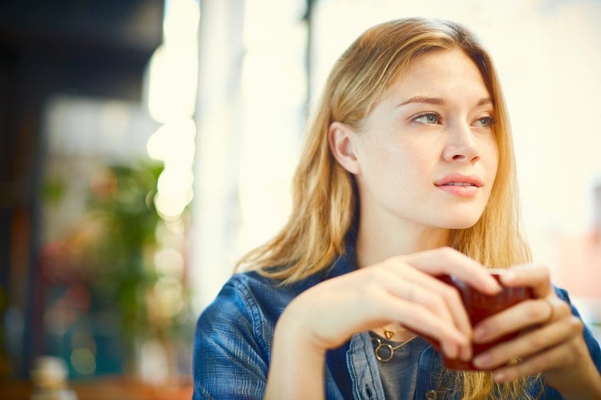 Thoughtful woman drinking coffee in cafe