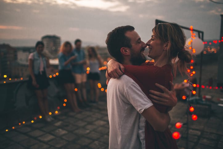 Couple of friends having a party on the rooftop of the building at sunset;