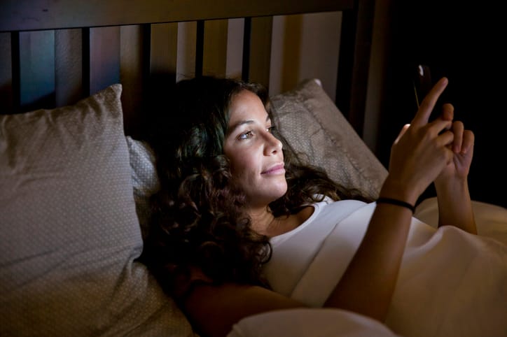 woman texting in bed