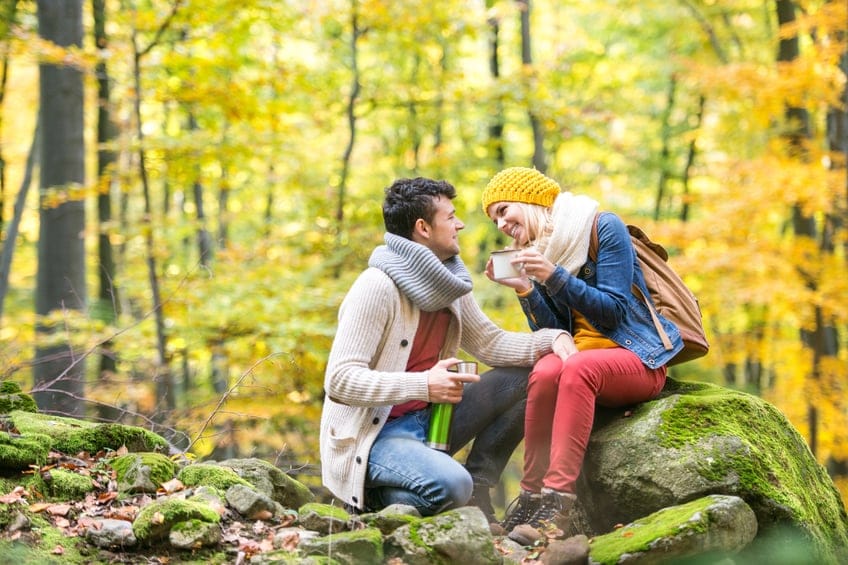 Beautiful couple in autumn forest, thermos and cup
