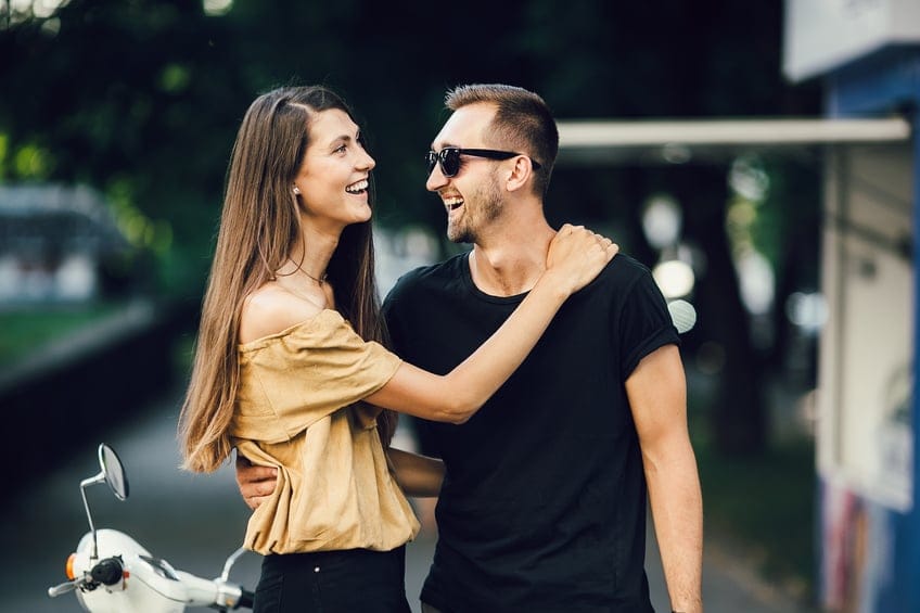 Cute couple with their scooter on a sunny day in the city