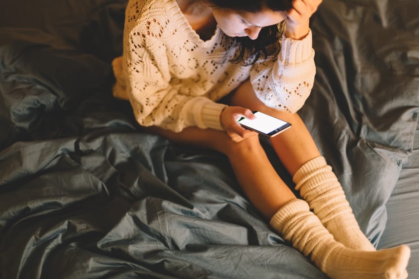 Girl in bed text messaging