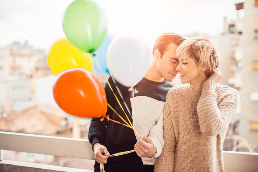 Young couple holding balloons.