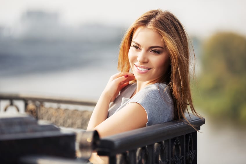 Happy young fashion woman at the cast iron fence