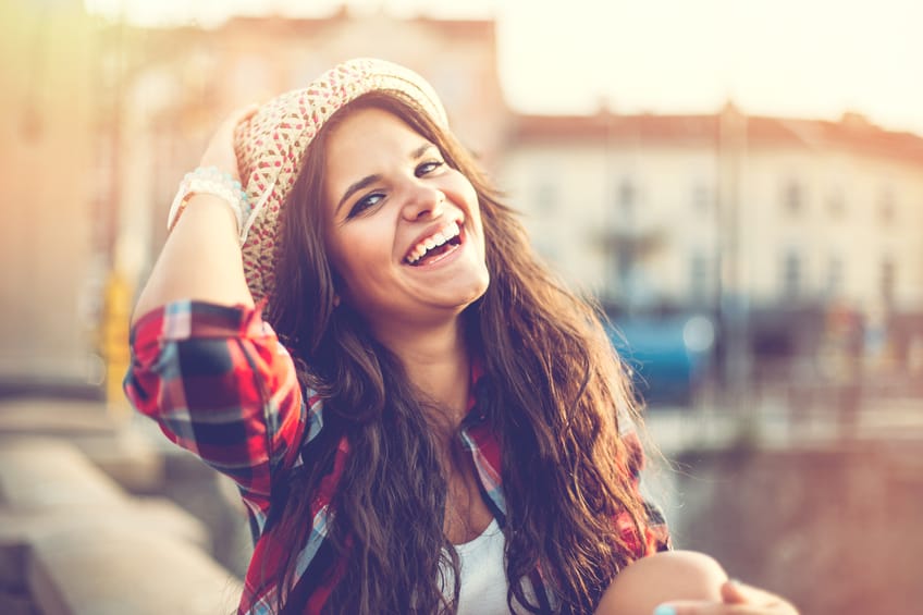 Smiling young woman with a hat in urban setting, with copy space