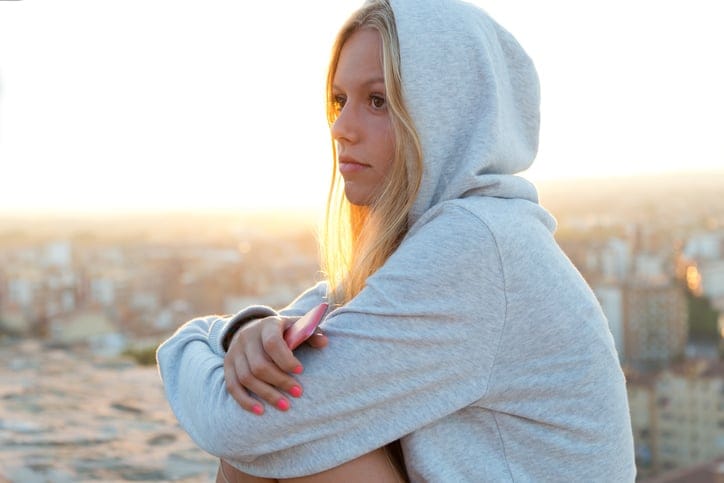 Outdoor portrait of beautiful girl sitting on the roof and listening to music.