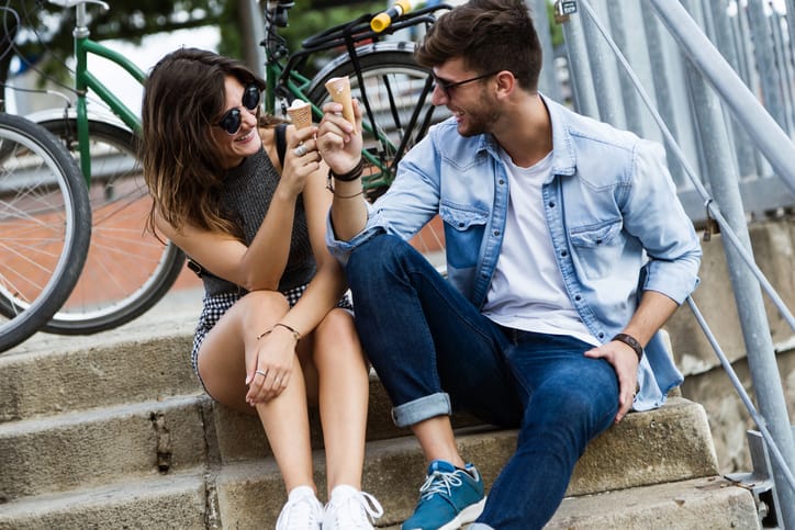 Portrait of happy young couple eating ice cream in the street.