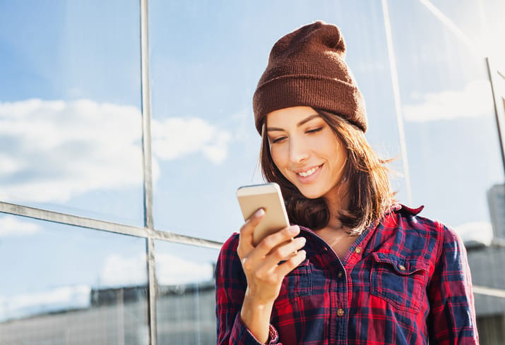 young woman texting outdoors sunshine portrait hipster