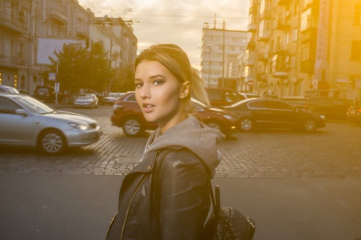 Young woman crossing the street in the city at dusk