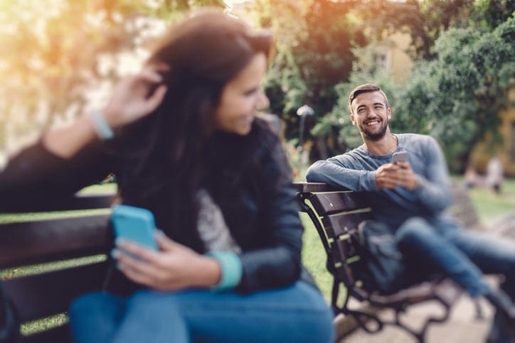 Happy couple using smartphones in the city park