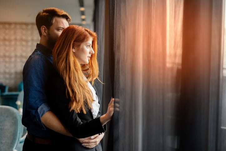 Romantic couple enjoying sunset from luxurious room