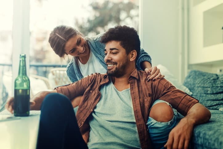 Young couple sitting on the bed in a living room and having fun together.
