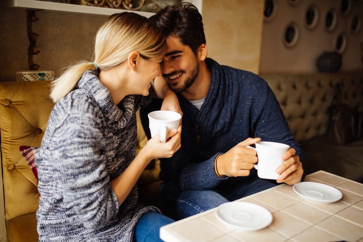 Young couple in love is enjoying spending time together while flirting over coffee in cafe.