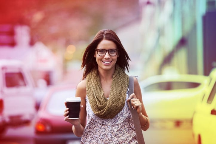 A gorgeous young woman enjoying some coffee while checking out the city