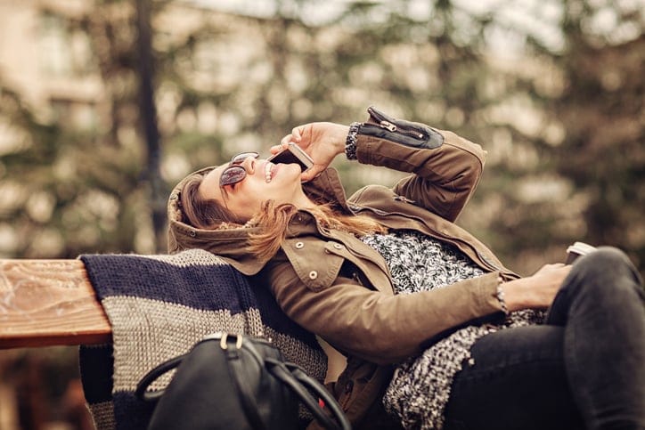 Close up of a young woman having phone conversation while sitting on the bench