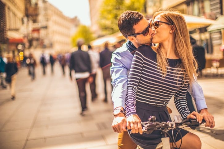Photo of young smiling couple riding a bicycle
