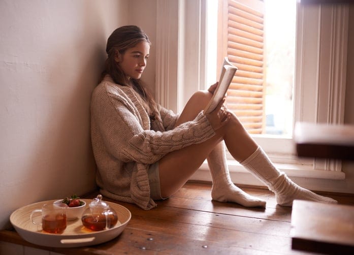 Girl sat reading book near window