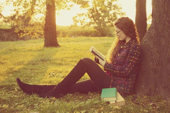 Carefree young woman reading a book and relaxing in the park.