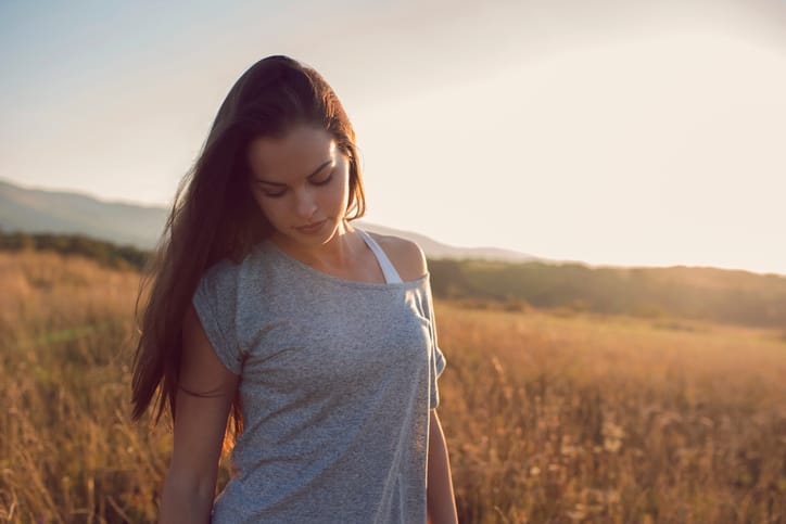 Beautiful caucasian woman standing in the grass field and enjoying the nature