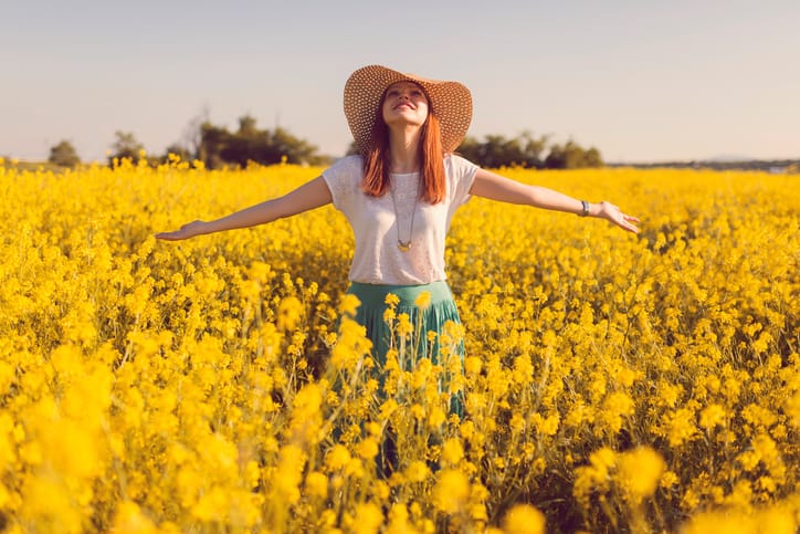Young woman standing in the middle of the flower meadow.
