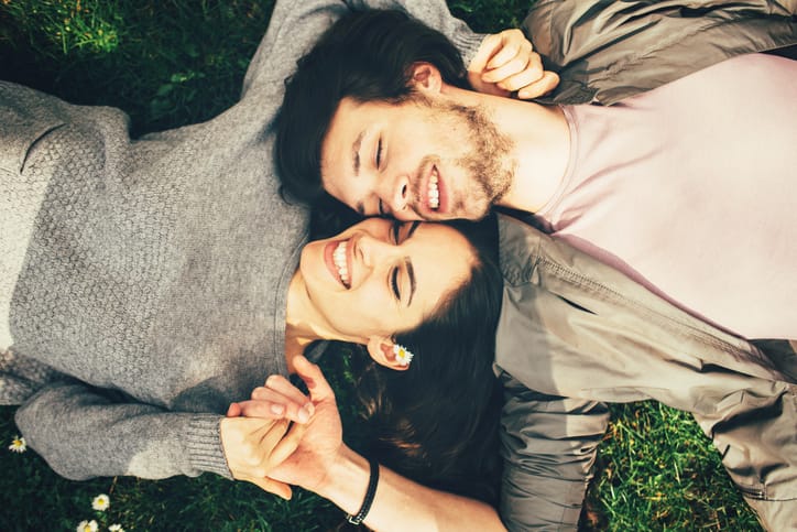 Happy young couple lying on the grass