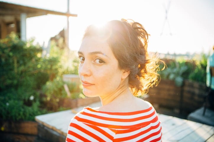 candid smiling young woman portrait in back lit, looking over shoulder