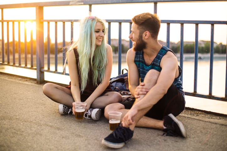 Beautiful teenage couple having fun, smiling and drinking beer