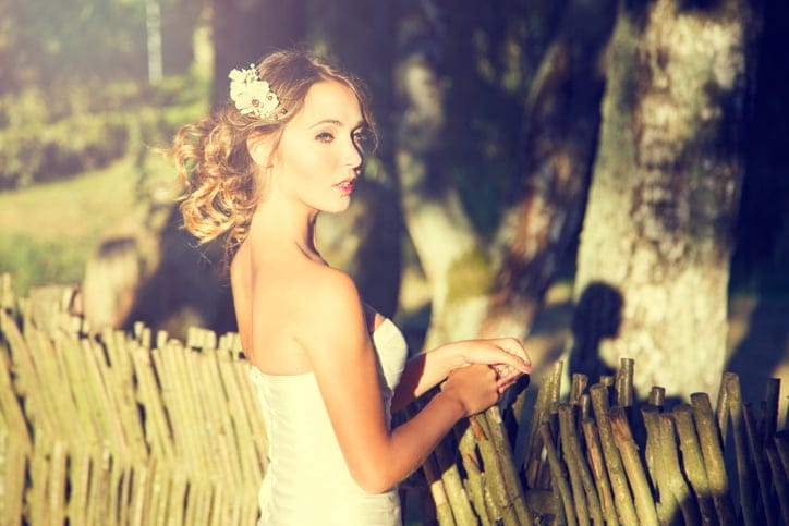 Stylish Young Bride Outdoors Portrait at Wooden Fence Background. Modern Wedding Hairstyle and Accessories. Sunset Light. Toned Photo with Copy Space.