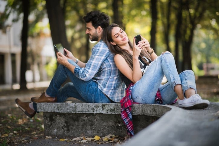 Urban couple in the park sitting back to back