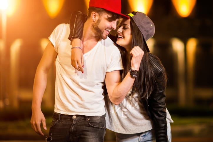Urban heterosexual couple in love sharing a hug during their date in the city at night.