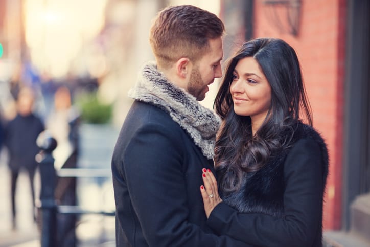Beautiful couple having a romantic embrace on a street outdoors during sunset.