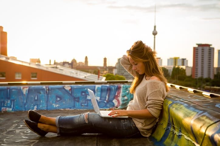 Berlin: young woman on a roof works at her laptop,