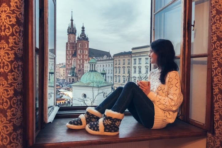 Happy woman drinking tea and looking through the window