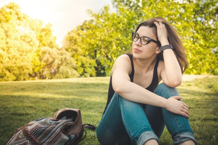 Beautiful woman enjoying summer sitting in a park on a grass.