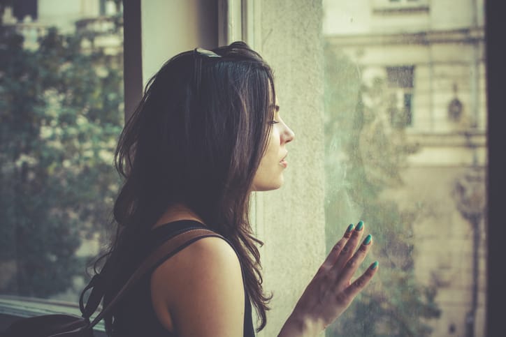 Young woman looking through the window