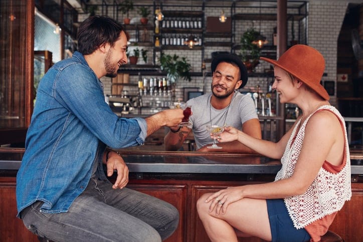 Portrait of young modern people sitting in the coffee shop and having their drinks. Group of friends at a cafe toasting drinks.