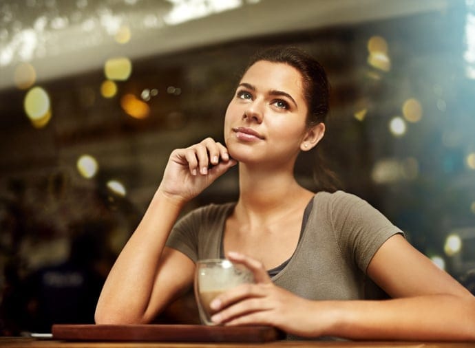 Shot of a young woman drinking a coffee while sitting in a cafe
